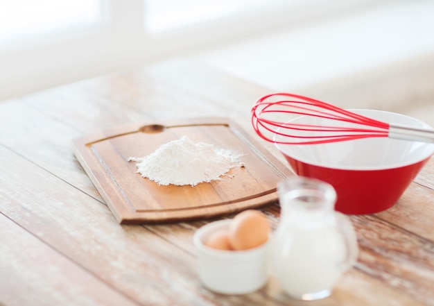 concetto di cucina e cibo - primo piano di brocca di latte, uova in una ciotola e farina