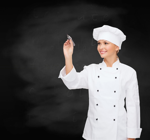 concetto di cucina, pubblicità e persone - chef femminile sorridente, cuoco o fornaio con pennarello che scrive qualcosa in onda su sfondo lavagna