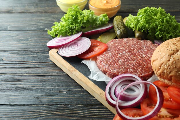 Concetto di cucinare hamburger su tavola di legno