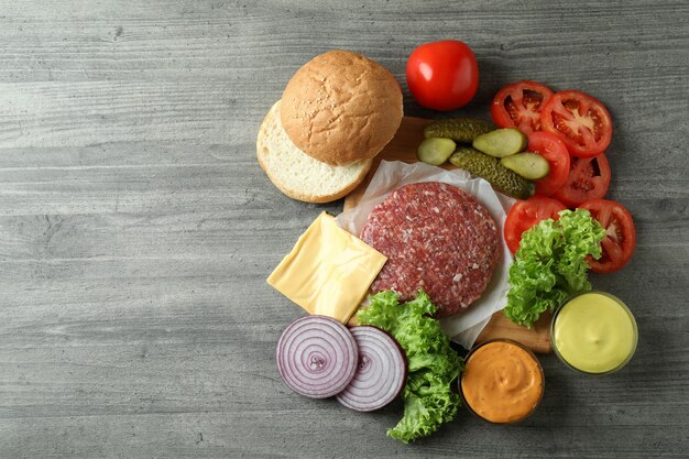 Concetto di cucinare hamburger su un tavolo strutturato grigio