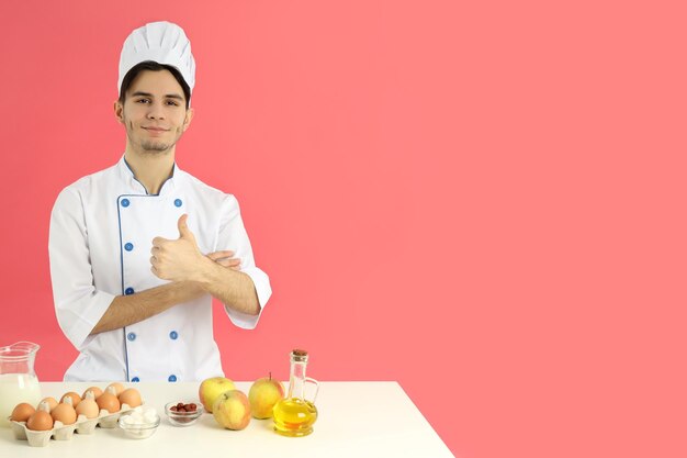 Concetto di cucinare il giovane chef maschio su sfondo rosa