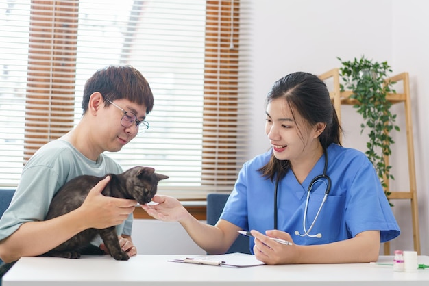 Concetto di cura degli animali Veterinario femminile che esamina il gatto e scrive la prescrizione sugli appunti