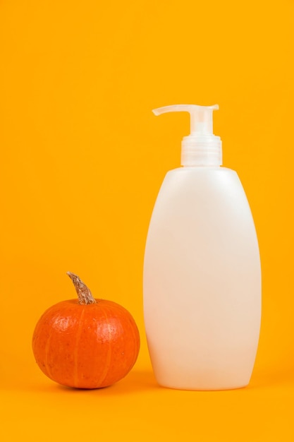 Concetto di cura della pelle autunnale Flacone cosmetico bianco foglie cadute gialle e zucca Mockup minimalista per la presentazione del prodotto