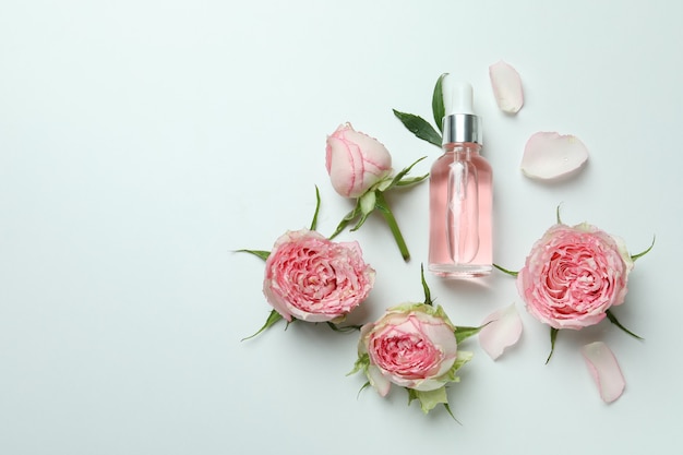 Concetto di cura della pelle con olio essenziale di rose e rose su bianco