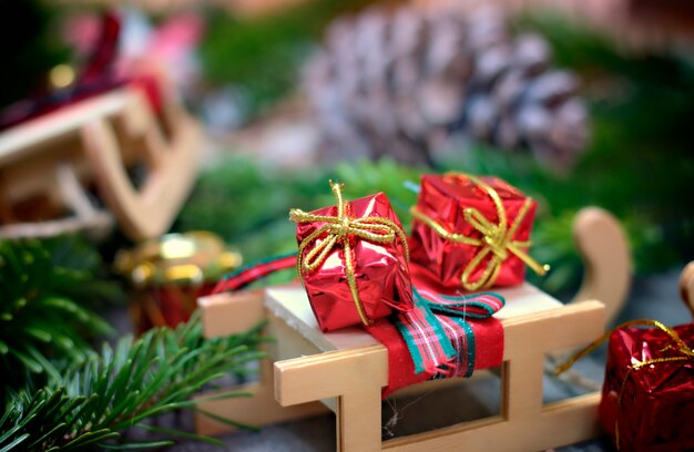 Concetto di decorazione e di Natale in su della slitta e regali su fondo di legno.