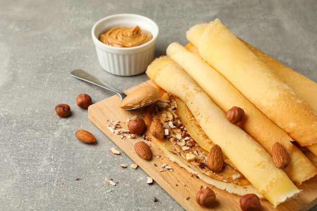 Concetto di deliziosa colazione con crepes con burro di arachidi e noci sul tavolo grigio