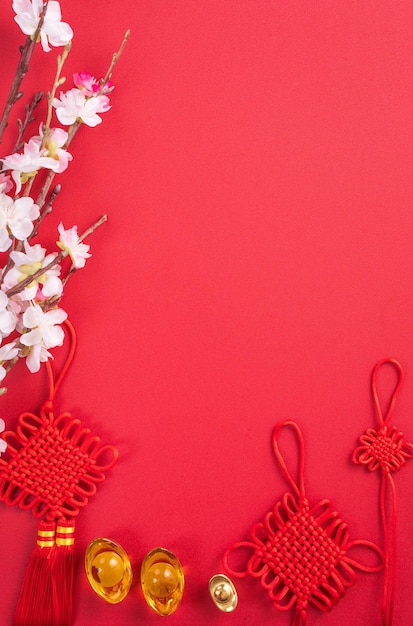 Concetto di design del capodanno lunare cinese - bellissimo nodo cinese con prugna fiore isolato su sfondo rosso, piatto laico, vista dall'alto, layout overhead.