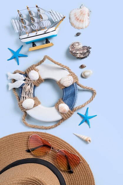 Concetto di design del fondo della spiaggia di estate. Vista dall'alto del viaggio di vacanza con conchiglie, cappello e occhiali da sole su sfondo blu.