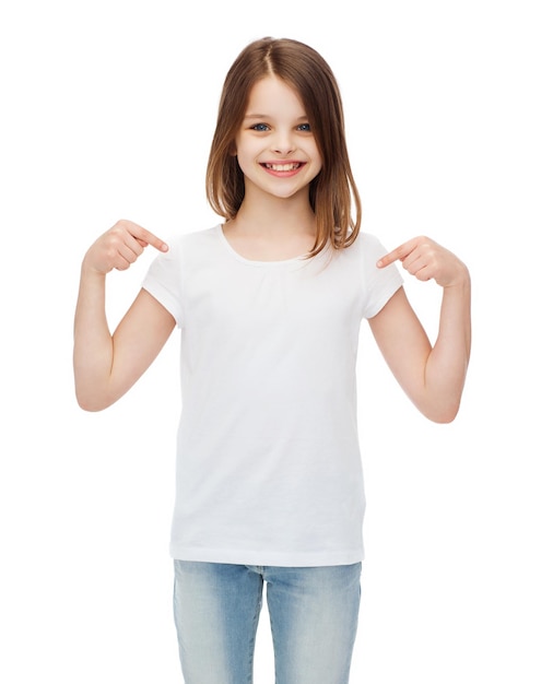 concetto di design t-shirt - bambina sorridente in t-shirt bianca vuota che punta a se stessa