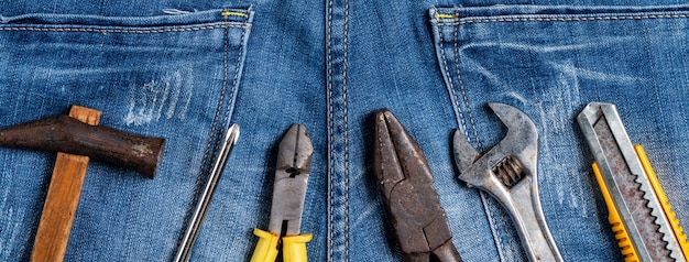 Concetto di design vista dall'alto della festa del lavoro con strumenti di lavoro su sfondo blu jeans.