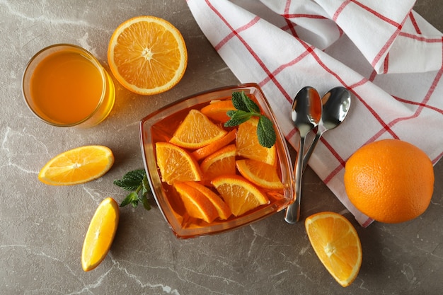 Concetto di dessert con ciotola di gelatina d'arancia con fette d'arancia sul tavolo grigio