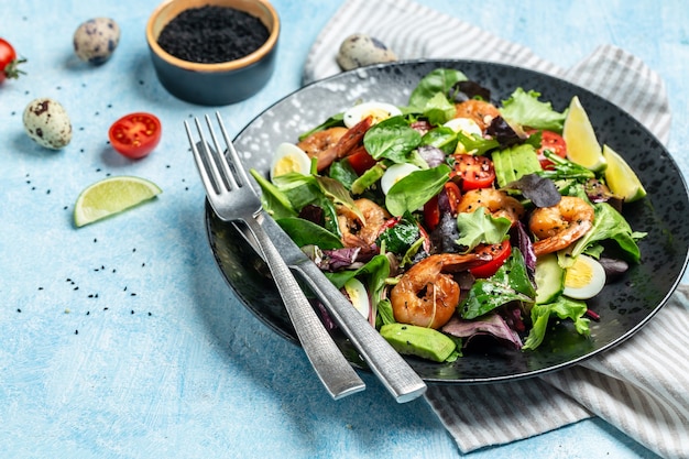 Concetto di dieta alimentare. Insalata verde con pomodorini, cetrioli, avocado, uova e gamberi affumicati. Deliziosa colazione o spuntino su uno sfondo chiaro, vista dall'alto.