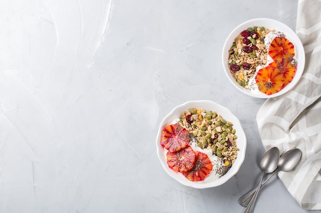 Concetto di dieta e nutrizione sana Colazione mattutina con muesli di muesli fatto in casa yogurt naturale arance rosse mature stagionali