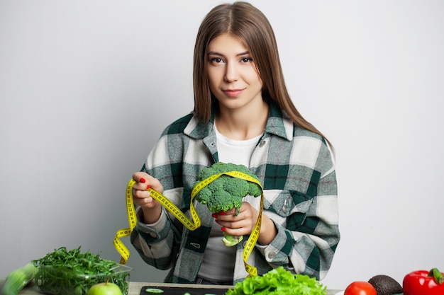 Concetto di dieta e ragazza sana di cibo con verdure sullo sfondo del muro bianco