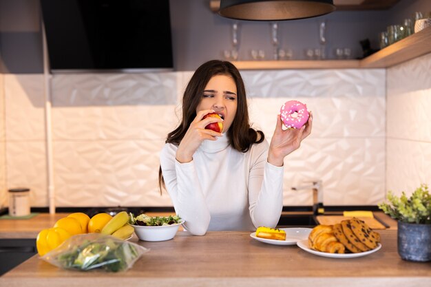 Concetto di dieta. Giovane Donna Che Sceglie Tra Frutta E Dolci.