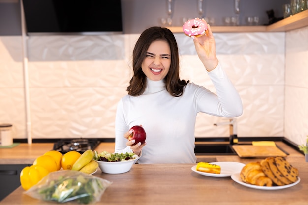 Concetto di dieta. Giovane Donna Che Sceglie Tra Frutta E Dolci.