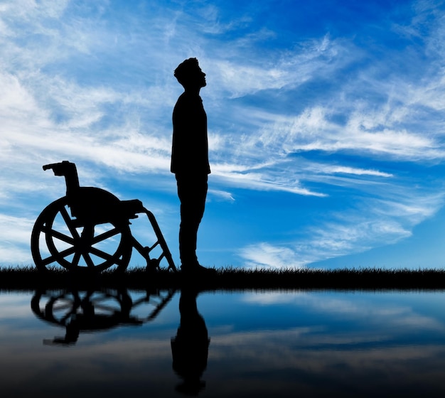 Concetto di disabilità e malattia. Silhouette di disabili e sedie a rotelle durante il giorno e riflesso nell'acqua