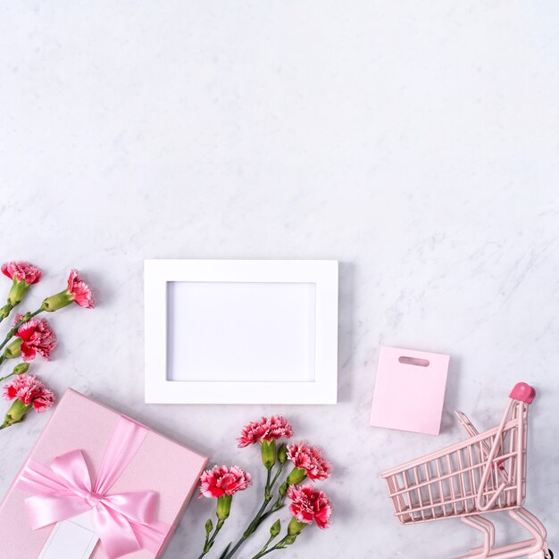 Concetto di disegno di saluto di festa della mamma con bouquet di garofani e regalo sulla superficie di marmo bianco