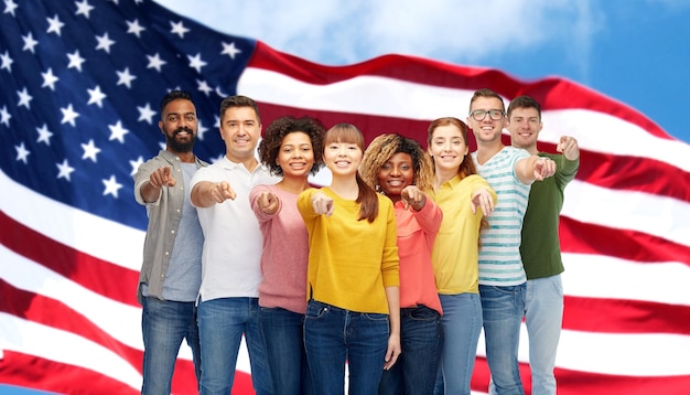 concetto di diversità, immigrazione e persone - gruppo internazionale di uomini e donne sorridenti felici che puntano il dito su di te sullo sfondo della bandiera americana