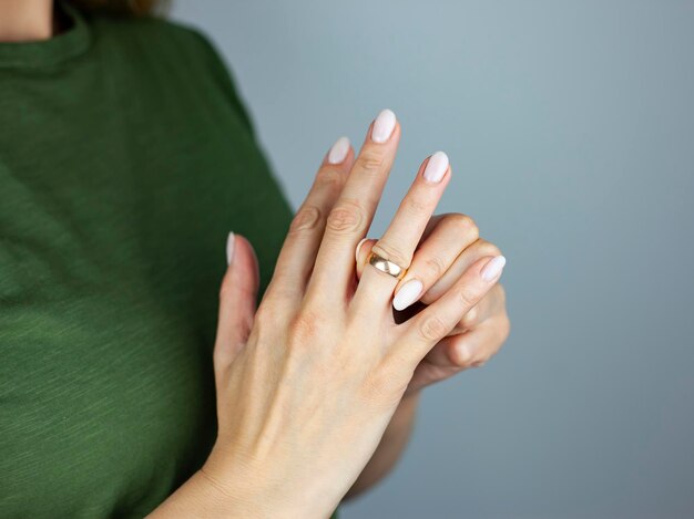 Concetto di divorzioUna giovane donna rimuove un anello nuziale dal dito