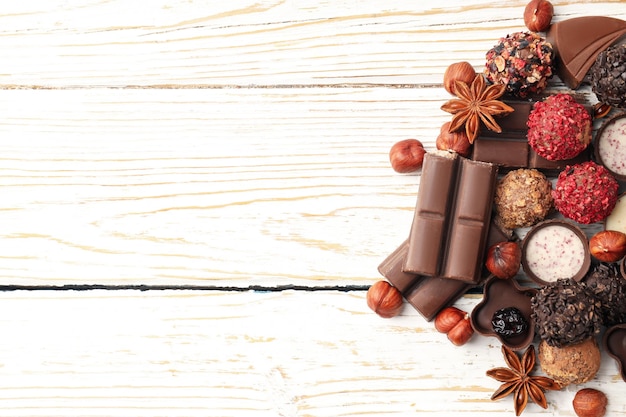 Concetto di dolci con cioccolatini su fondo di legno bianco