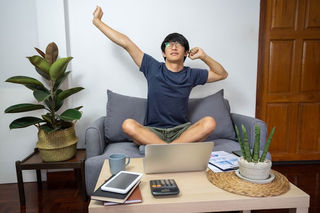 Concetto di e-commerce un uomo che indossa la t-shirt blu e i pantaloncini verdi che sembra stanco per aver lavorato a lungo.