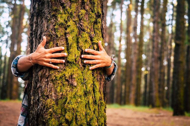 Concetto di ecologia e ambiente con donna caucasica che abbraccia un albero verde nella foresta all'aperto