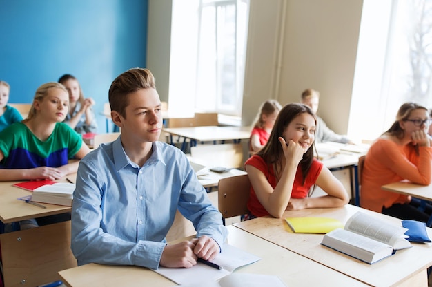 concetto di educazione, apprendimento e persone - gruppo di studenti con quaderni a lezione di scuola