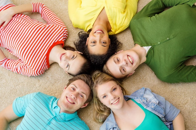 concetto di educazione e felicità - gruppo di giovani sorridenti sdraiati sul pavimento in cerchio