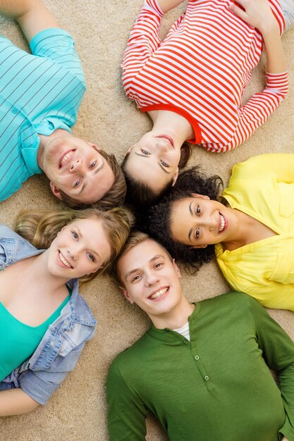 concetto di educazione e felicità - gruppo di giovani sorridenti sdraiati sul pavimento in cerchio