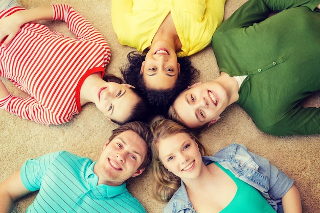 concetto di educazione e felicità - gruppo di giovani sorridenti sdraiati sul pavimento in cerchio