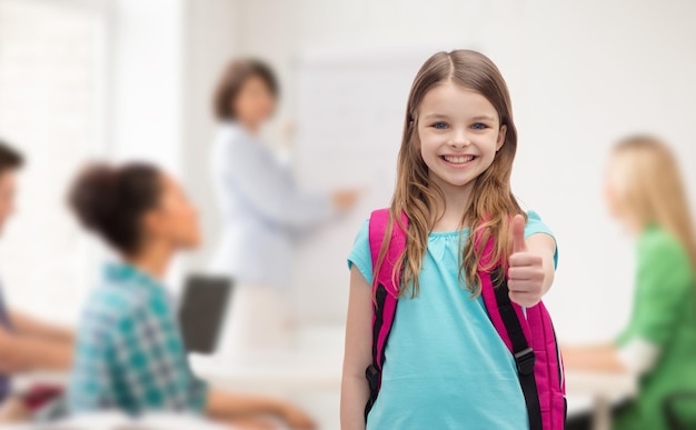 concetto di educazione, gesto e scuola - bambina felice e sorridente con la borsa della scuola che mostra i pollici in su