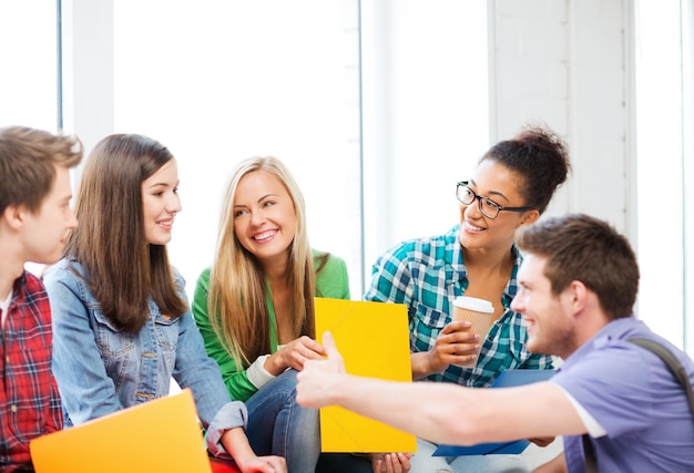 concetto di educazione - studenti che comunicano e ridono a scuola