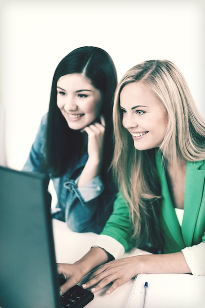 concetto di educazione - studenti che guardano il laptop a scuola