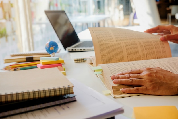 Concetto di educazione. Studenti che studiano e brainstorming il concetto del campus. Primo piano di studenti che discutono il loro tema sui libri di libri e la scrittura a notebook. Messa a fuoco selettiva.