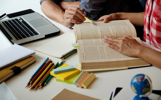 Concetto di educazione. Studenti che studiano e brainstorming il concetto del campus. Primo piano di studenti che discutono il loro tema sui libri di libri e la scrittura a notebook. Messa a fuoco selettiva.