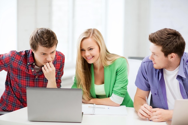 concetto di educazione - studenti sorridenti che guardano il laptop a scuola