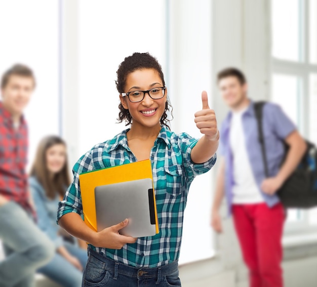 concetto di educazione, tecnologia e persone - studentessa afroamericana sorridente in occhiali con cartelle e tablet pc a scuola