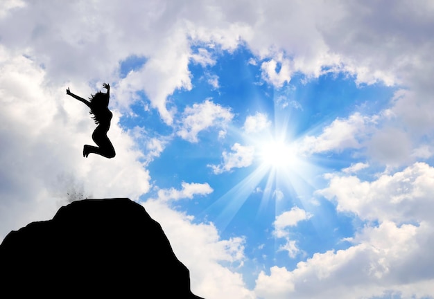 Concetto di emozioni e sentimenti. Silhouette di donna felice che salta sulla cima di una montagna