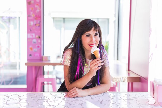 Concetto di estate, della gioventù e del dessert - Ragazza graziosa che gode di un cono gelato in caffè