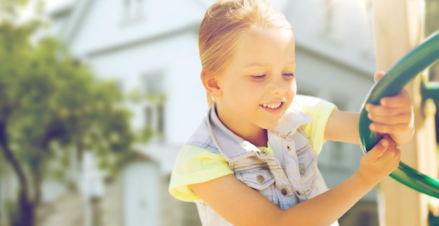 concetto di estate, infanzia e persone - bambina felice sul parco giochi per bambini struttura da arrampicata su sfondo di casa vivente