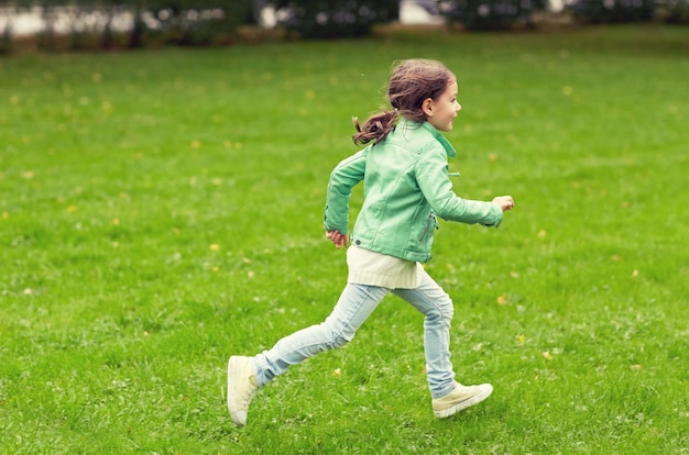 concetto di estate, infanzia, tempo libero e persone - bambina felice che corre sul campo estivo verde