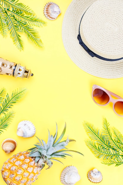 Concetto di estate tropicale con accessori moda donna, foglie e ananas su sfondo giallo. Vista piana, vista dall'alto