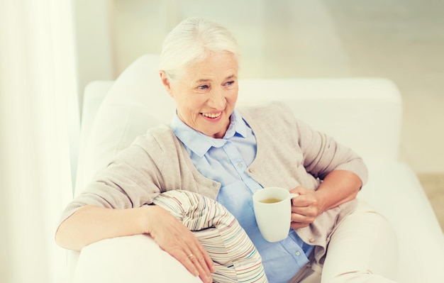 concetto di età, bevanda e persone - donna anziana sorridente felice con una tazza di tè a casa