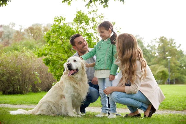 concetto di famiglia, animale domestico, animale domestico e persone - famiglia felice con cane labrador retriever sulla passeggiata nel parco