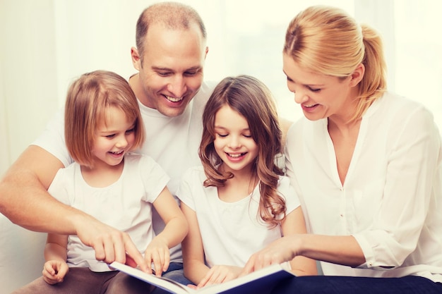 concetto di famiglia, bambini e casa - famiglia sorridente e due bambine con il libro a casa