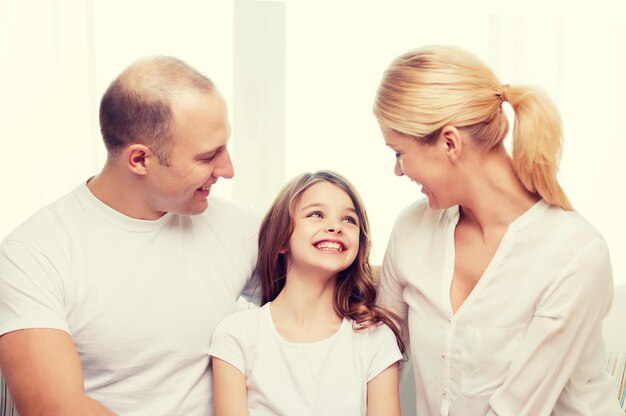 concetto di famiglia, bambino e casa - genitori sorridenti e bambina a casa