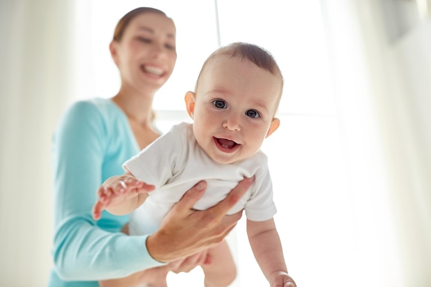 Concetto di famiglia, bambino e genitorialità - giovane madre sorridente felice con un bambino piccolo a casa