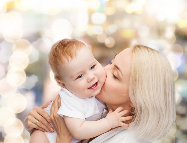 concetto di famiglia, bambino e genitorialità - madre felice che bacia bambino sorridente