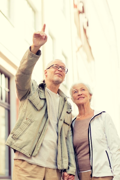 concetto di famiglia, età, turismo, viaggi e persone - coppia senior sulla strada della città